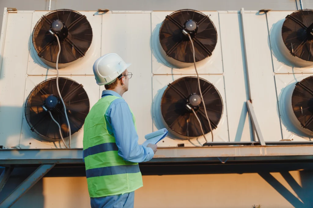a commercial air conditioning installer in hi vis taking notes of the current air conditioning system for replacement