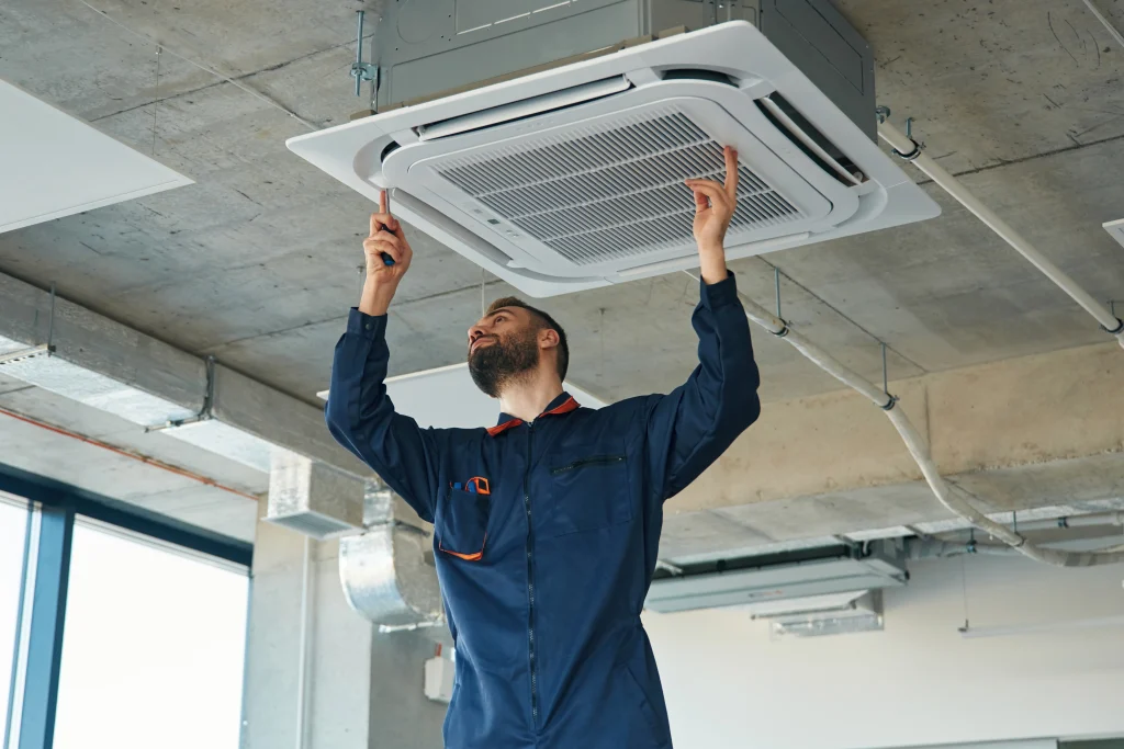 Commercial air conditioning installation engineer fitting a ceiling cassette air conditioning unit