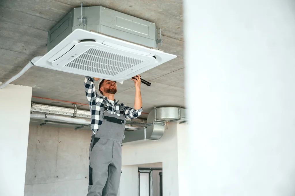 an industrial air conditioning installer replacing an ac unit while stood on a ladder